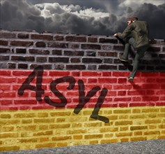 Man climbing over a wall with German flag and writing asylum