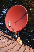 Red satellite dish on a roof of a residential house