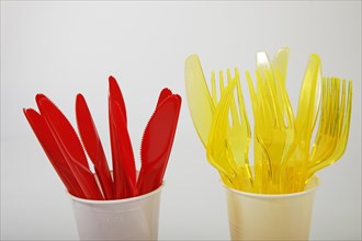 Red and yellow plastic cutlery in plastic cups