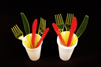 Red and yellow plastic cutlery in white plastic cups