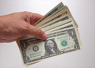 Hand holds bundles of U.S. dollars