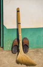 Broom and shoes against wall