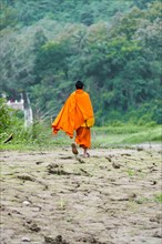 Buddhist monk running along banks of Mekong