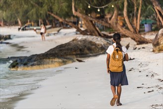 Local girls walking to school on idyllic sandy beach at Koh Tui Beach