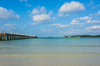 Pier on beach with boats in turquoise water at Saracen Bay on Koh Rong Sanloem island