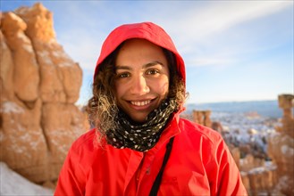 Portrait of a pretty young woman in winter clothes in front of rock needles