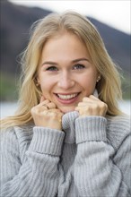 Portrait of a laughing young woman with long blond hair umd warm sweater