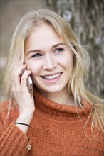 Blonde young woman phoning with a mobile