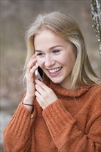 Blond young woman phoning with a mobile