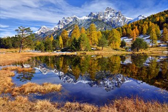 Snow-covered mountains and autumnal larch forest reflected in the Lai Nair