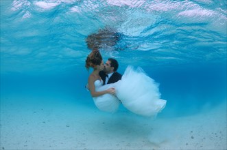 Newlyweds kissing underwater
