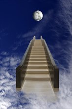 Long staircase leading up into the dark blue sky with moon and clouds