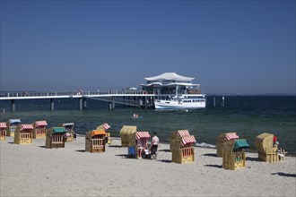 Beach chairs on Timmendorfer beach with Seeschlosschenbrucke bridge and Japanese teahouse