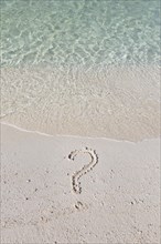 Question mark written out in sand on a beach