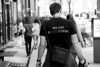 Man walking down the street wearing a T-shirt with the inscription We Are Revolution