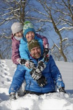 Father and his children rollicking in the snow