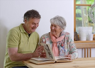Grown-up son and elderly mother looking at a photo album