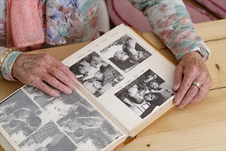 Hands of an elderly woman leafing through an old photo album