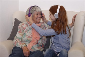 Granddaughter and grandmother listening to music through headphones