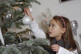 Girl decorating a Christmas tree with baubles