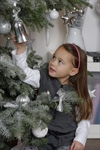 Girl at the Christmas tree with Christmas decorations