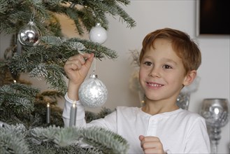 Boy decorating a Christmas tree with baubles