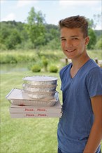 Boy holding cardboard boxes with pizzas