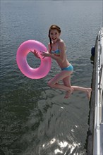 Girl with pink floating tire jumps into the water