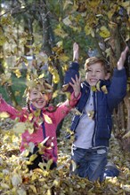 Children playing with autumn leaves