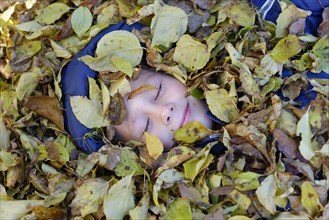 Boy lying in autumn foliage