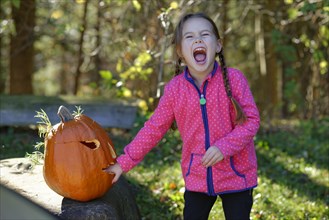 Girl with a Halloween pumpkin in autumn