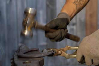 Blacksmith hands shaping horseshoe with hammer
