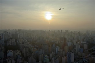 Helicopter above a cityscape with skyscrapers at sunset