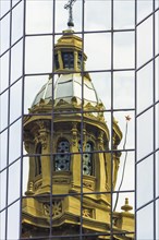 Cathedral tower reflecting in a glass building