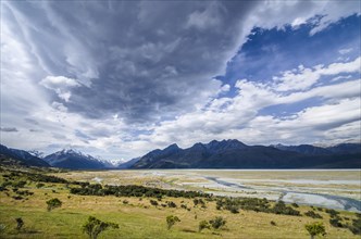 Grassland in front of the wide riverbed of the Tasman River