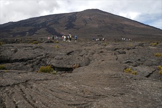 Hikers hike through lava landscape