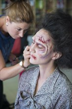 Actress being painted by makeup artist as a zombie for the zombie comedy Brain Freeze