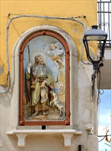 Painting of patron saint on a wall with power cables