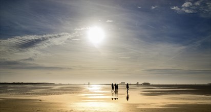 Walkers on the beach at sunset