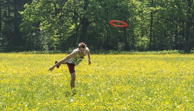 Young man throwing frisbee in meadow