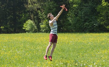 Young man catching frisbee in meadow