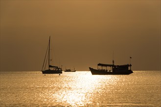 Two boats in sea at sunset