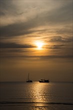 Two boats in sea at sunset