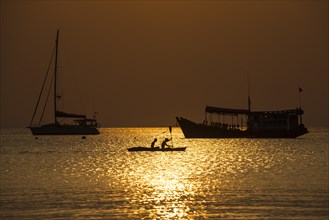 Boats and two kayakers in sea at sunset