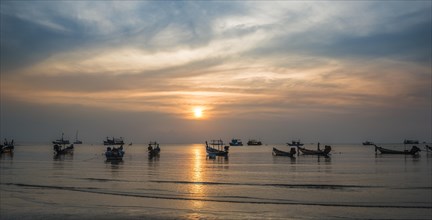 Long-tail boats in sea at sunset