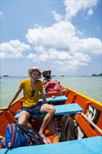 Young man sitting in longtail boat