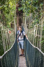 Young male tourist on a suspension bridge in the jungle