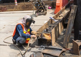 Construction worker welding a steel beam on a construction site