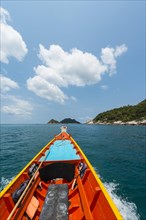Bow of a moving longtail boat in the turquoise sea