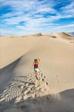 Tourist running down a sand dune